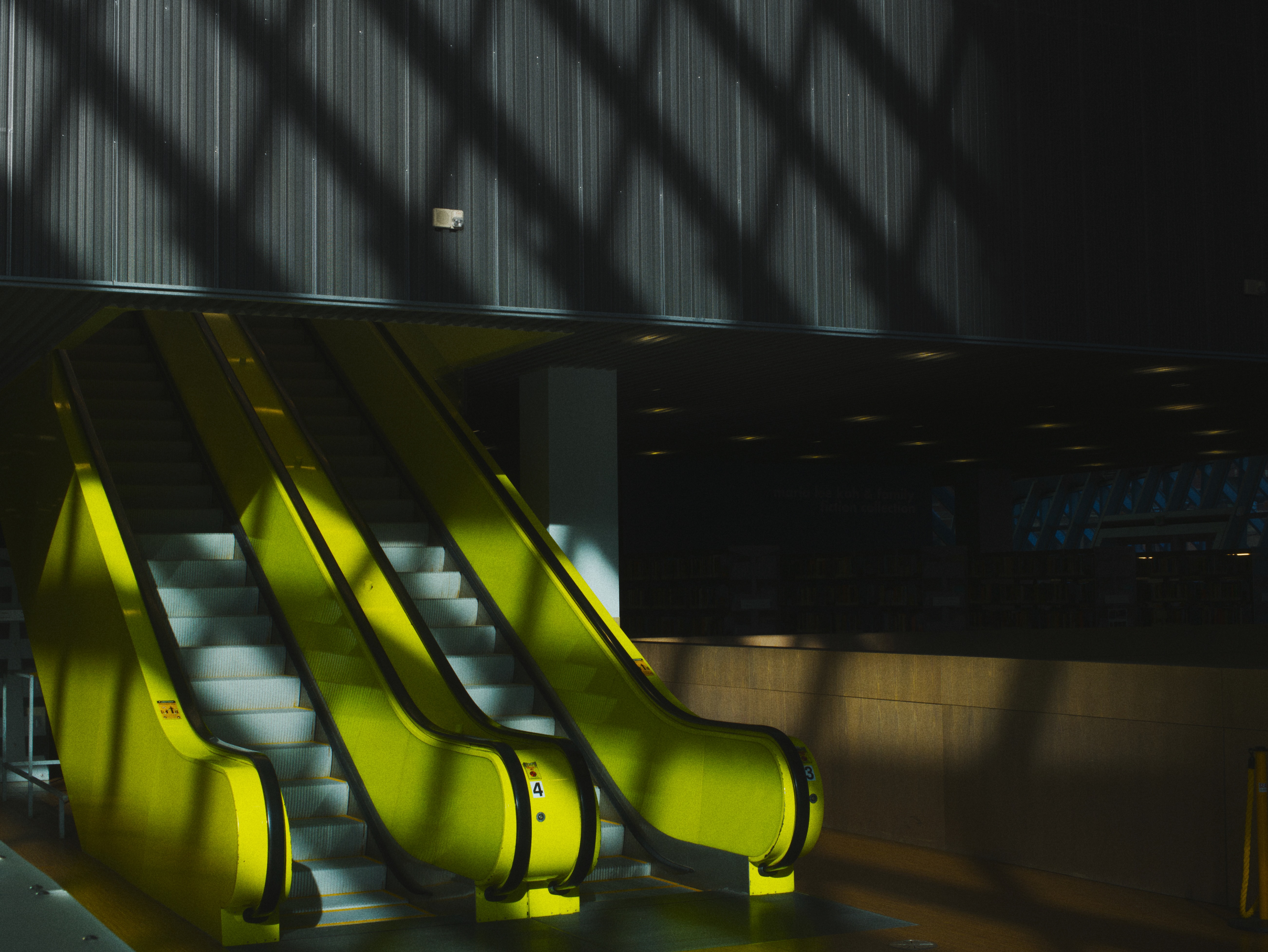A pair of bright yellow escalators with numbered indicators dimly lit